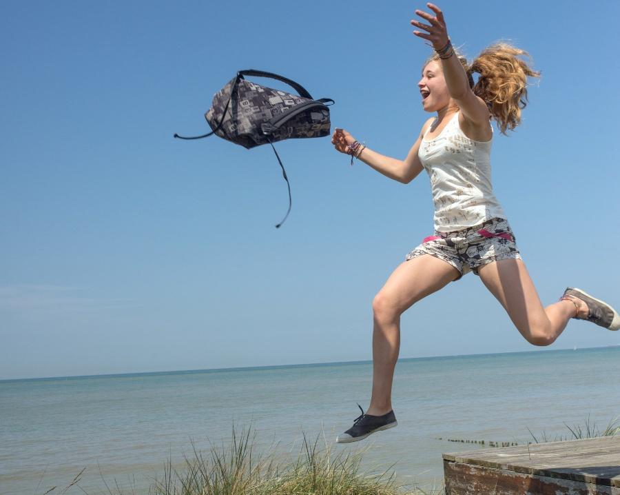 Mädchen springt, Rucksack fliegt durch die Luft - Schulranzen sauber machen