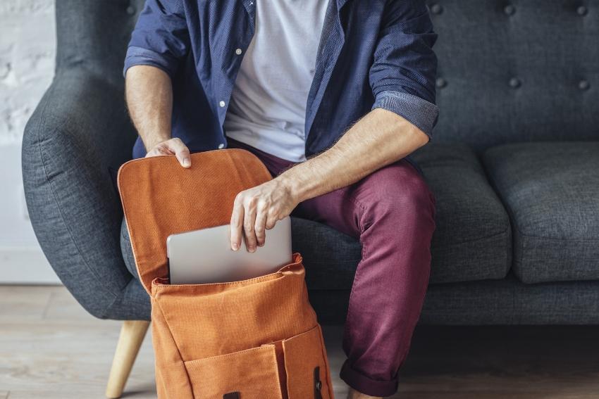 Mann steckt Laptop in deinen Rucksack