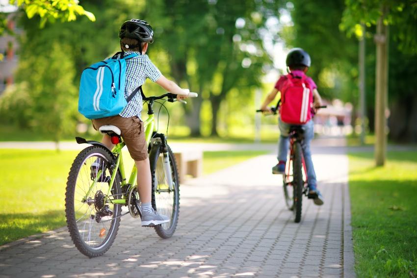 2 Kinder mit Schulrucksäcken auf dem Fahrrad - Schulranzen mit Reflektorstreifen
