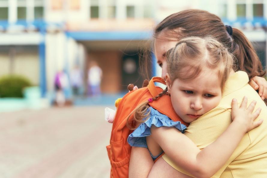 Maedchen umarmt sorgenvoll die Mutter - Angst vor der Einschulung