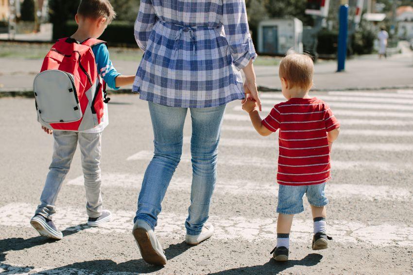 Mutter geht mit 2 Kindern über einen Zebrastreifen - Kindersicherheit im Straßenverkehr