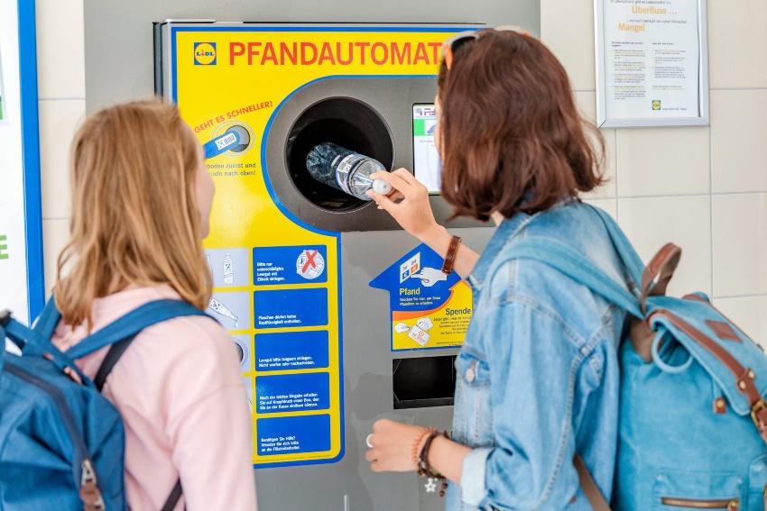 Zwei junge Frauen geben an einem Pfandautomaten eine leere PET-Flasche zurück - Upcycling aus PET-Flaschen