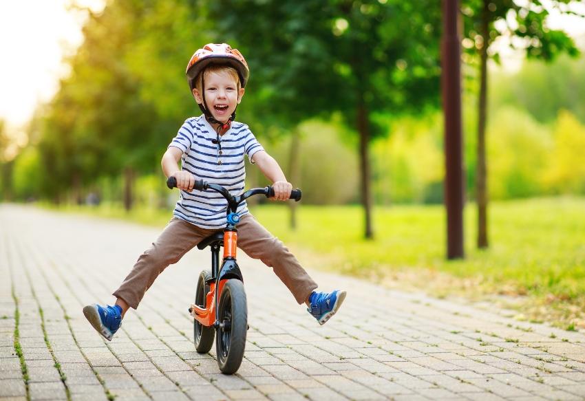 Kind fährt mit gespreizten Beinen auf kleine Fahrrad