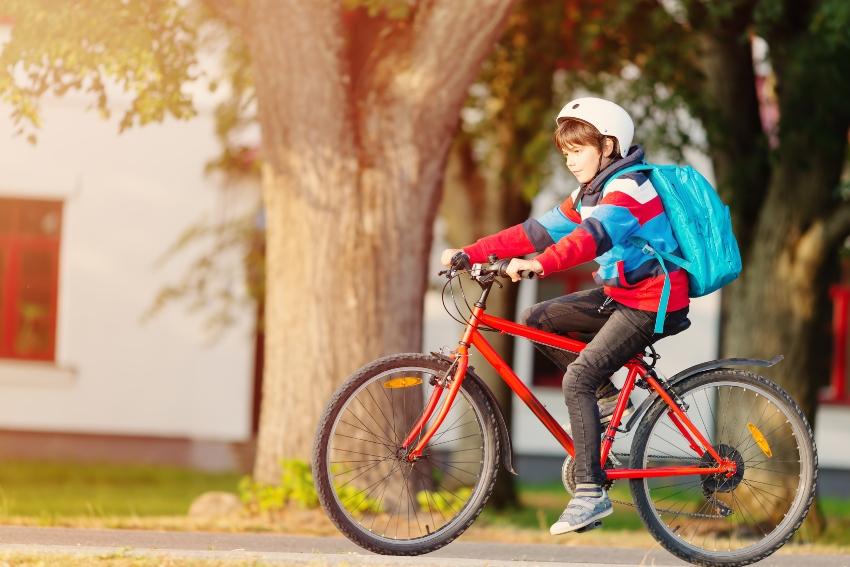Junger Schüler fährt auf Fahrrad - Schulrucksäcke für Jungen