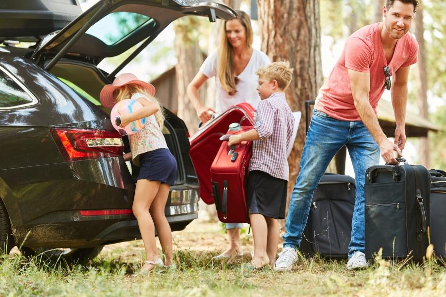 Junge Familie lädt Koffer ins Auto - Hartschale oder Weichgepäck
