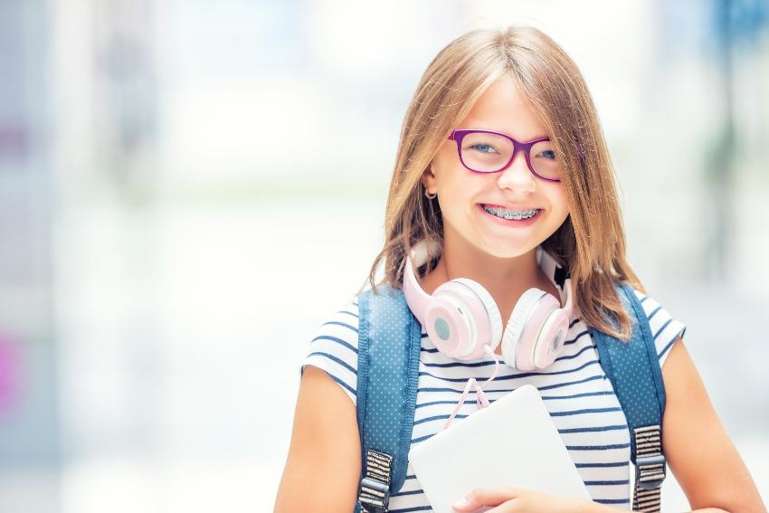 Mädchen mit Schulrucksack und pinkem Kopfhörer
