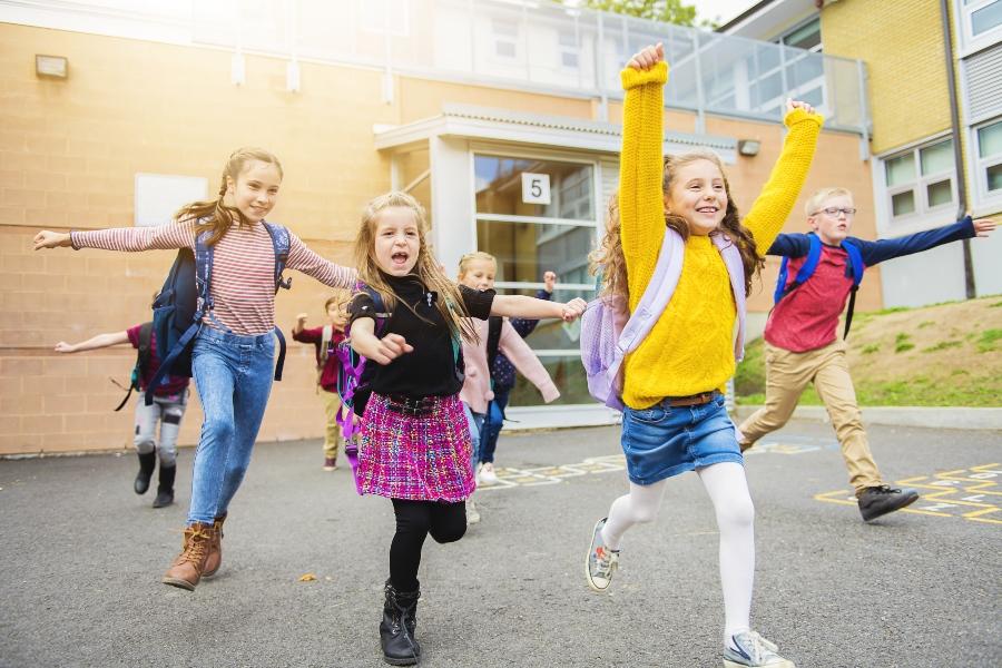 Junge Schulkinder rennen aus der Schule -ein bequemer Rucksack ist wichtig