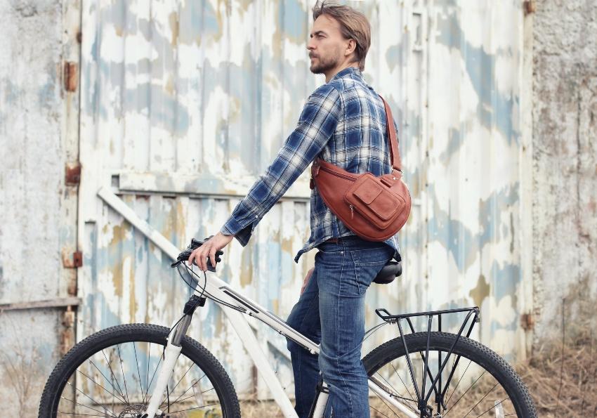 Junger Mann mit Fahrrad - eine Crossover-Tasche hat er dabei