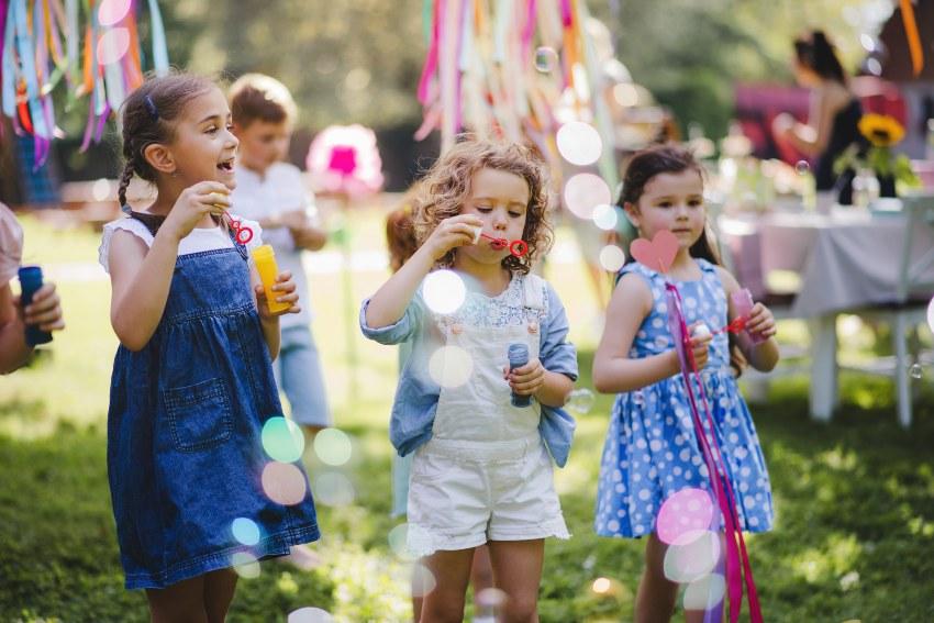 Kinder feiern im Garten mit Seifenblasen